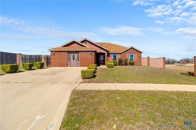 view of front facade with brick siding, concrete driveway, a front yard, and fence