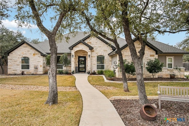 french country home featuring a front lawn and roof with shingles