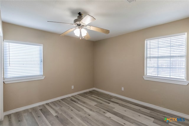 spare room featuring ceiling fan, a healthy amount of sunlight, and light wood-type flooring