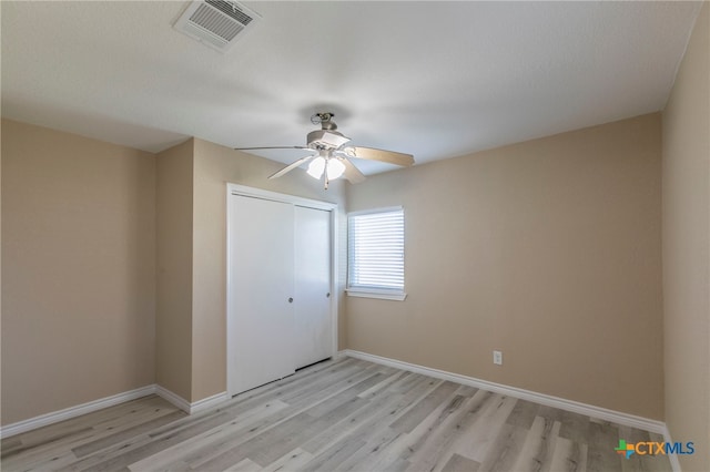 unfurnished bedroom featuring ceiling fan, light hardwood / wood-style floors, and a closet