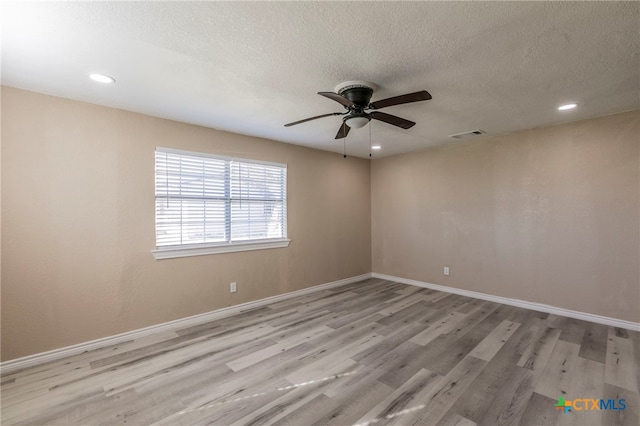 spare room with ceiling fan, a textured ceiling, and light hardwood / wood-style flooring