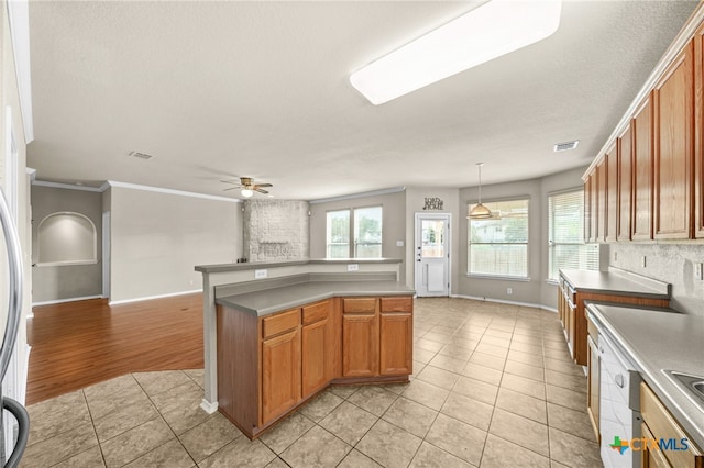 kitchen with ceiling fan, a textured ceiling, hanging light fixtures, crown molding, and light wood-type flooring