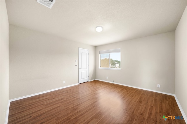 spare room featuring hardwood / wood-style floors and a textured ceiling