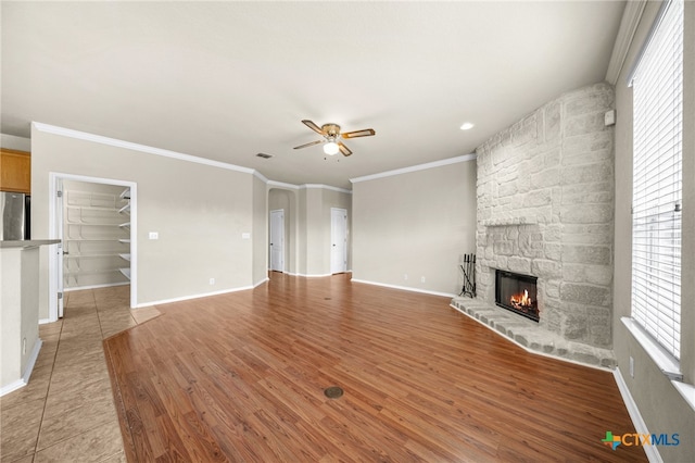 unfurnished living room featuring a fireplace, wood-type flooring, ceiling fan, and ornamental molding