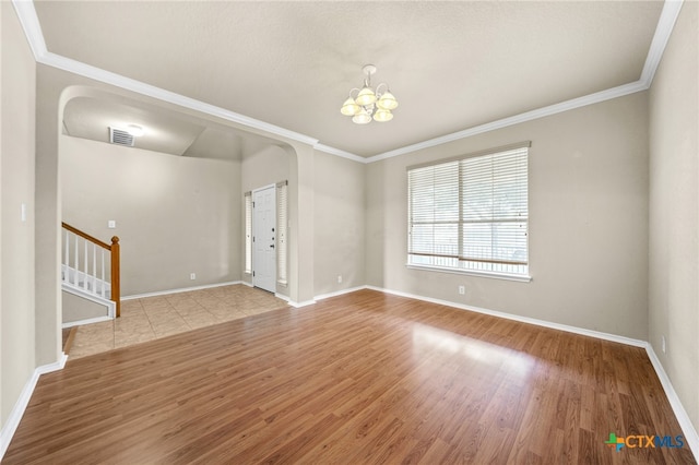 empty room featuring ornamental molding, light hardwood / wood-style flooring, and a notable chandelier