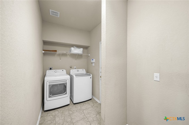 laundry room with separate washer and dryer and light tile patterned floors