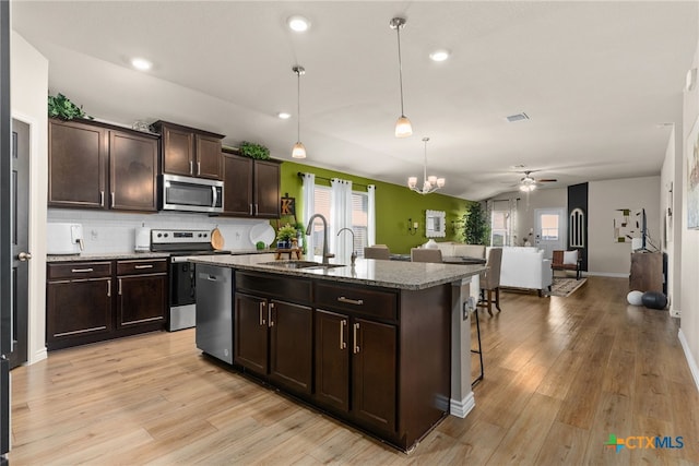 kitchen with a wealth of natural light, appliances with stainless steel finishes, sink, and a kitchen island with sink