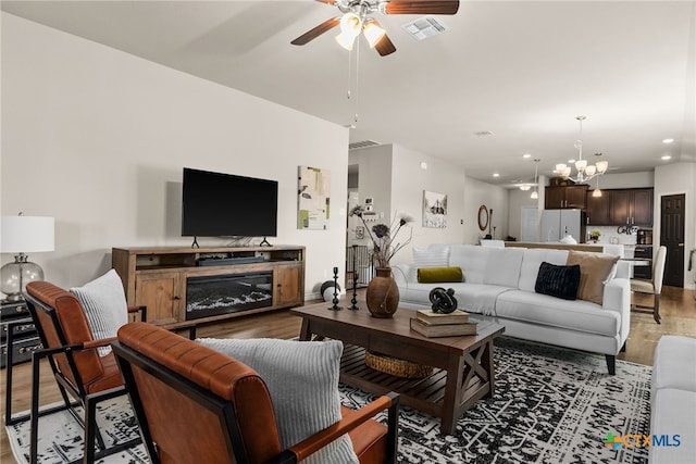 living room featuring wood-type flooring and ceiling fan with notable chandelier