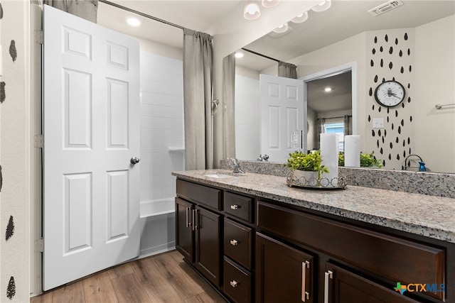 bathroom with hardwood / wood-style floors, vanity, and shower / tub combo