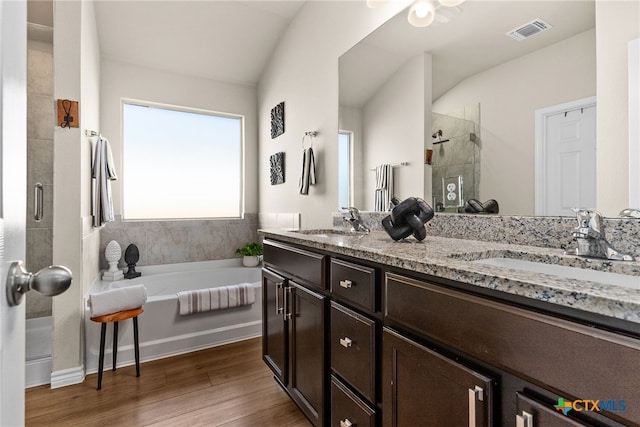 bathroom featuring vanity, plus walk in shower, vaulted ceiling, and hardwood / wood-style flooring