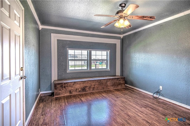 unfurnished room featuring baseboards, a textured wall, wood finished floors, and crown molding