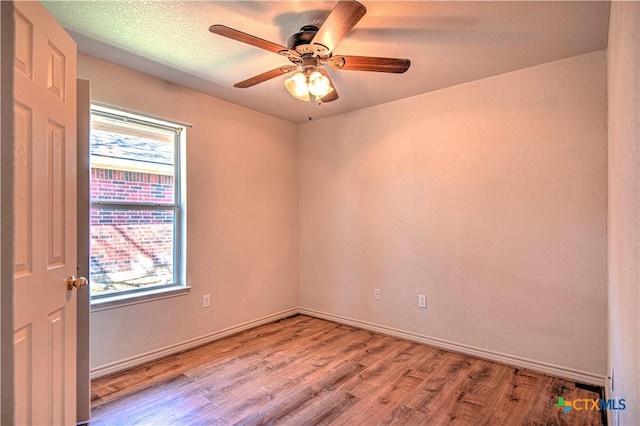 spare room featuring light wood-style floors, a ceiling fan, baseboards, and a textured ceiling