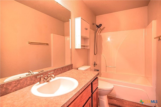 bathroom with a textured wall, vanity, shower / tub combination, and toilet