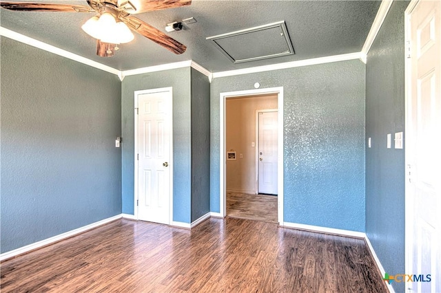 empty room with crown molding, a textured wall, baseboards, and wood finished floors