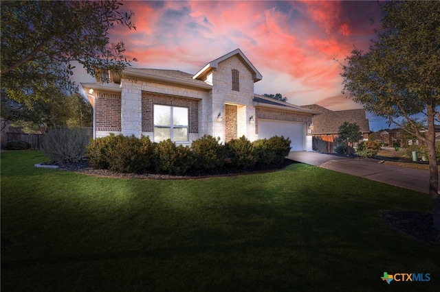 view of front of property featuring a garage, stone siding, a yard, and concrete driveway