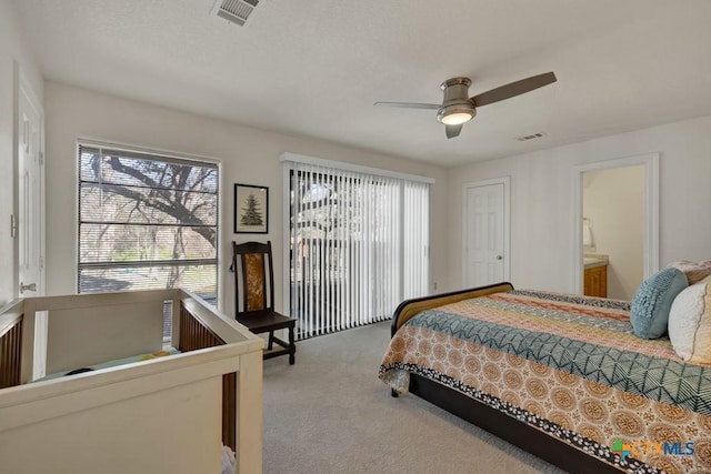 carpeted bedroom featuring visible vents, ensuite bathroom, and ceiling fan