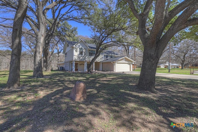 view of front of property featuring concrete driveway, a garage, and a front yard