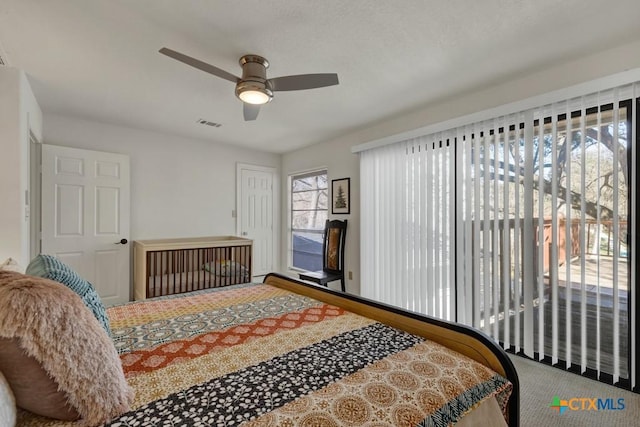 carpeted bedroom featuring a ceiling fan and visible vents