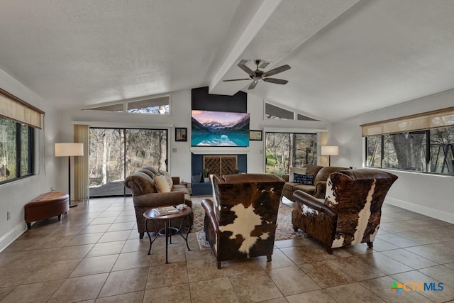 tiled living room with a ceiling fan, baseboards, vaulted ceiling with beams, a fireplace with raised hearth, and a textured ceiling