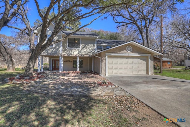 traditional-style house featuring concrete driveway, a garage, and a front lawn