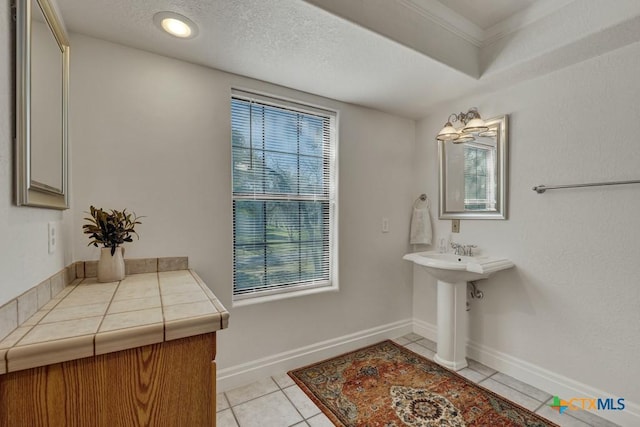 bathroom with tile patterned floors, a textured ceiling, and baseboards