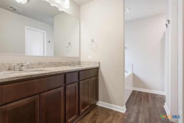 610 Hobby Rd, Copperas Cove, TX 76522 - bathroom featuring double vanity, wood finished floors, a sink, visible vents, and baseboards