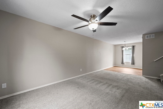 empty room featuring ceiling fan with notable chandelier, a textured ceiling, and carpet flooring