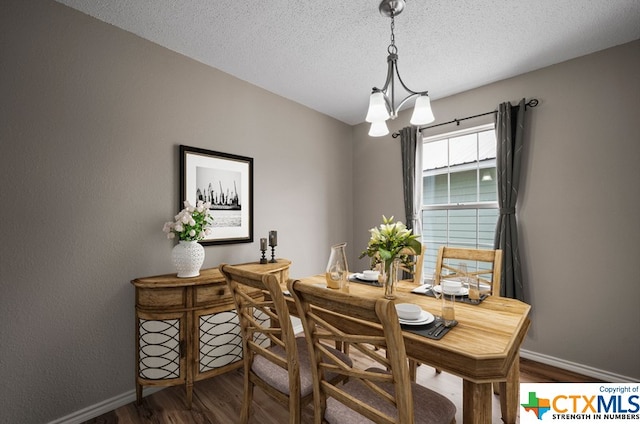 dining space featuring dark hardwood / wood-style flooring, a textured ceiling, and an inviting chandelier