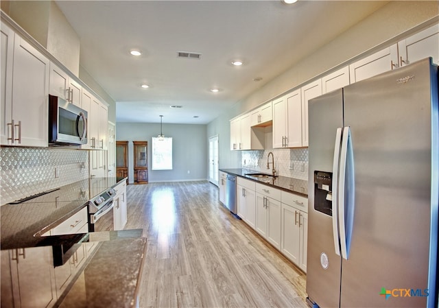 kitchen featuring light hardwood / wood-style floors, sink, appliances with stainless steel finishes, decorative light fixtures, and white cabinets