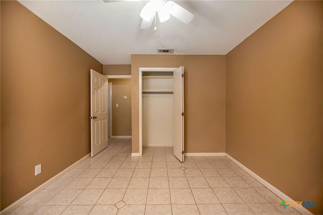 unfurnished bedroom featuring ceiling fan, light tile patterned floors, a textured ceiling, and a closet