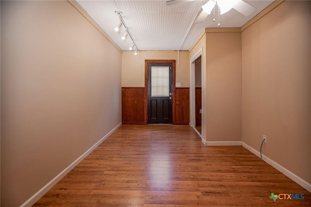 hallway with hardwood / wood-style floors, rail lighting, and ornamental molding