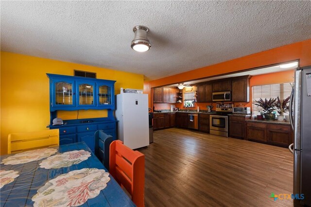 725 Baffin Dr, Port Mansfield, TX 78598 - kitchen with stainless steel appliances, dark wood-style flooring, a textured ceiling, glass insert cabinets, and dark countertops