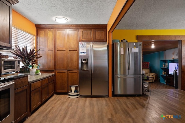 725 Baffin Dr, Port Mansfield, TX 78598 - kitchen with stainless steel fridge with ice dispenser, freestanding refrigerator, light wood finished floors, a textured ceiling, and brown cabinets