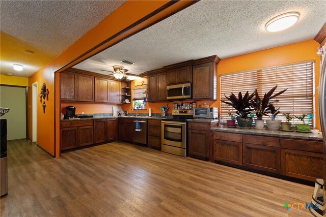 725 Baffin Dr, Port Mansfield, TX 78598 - kitchen featuring appliances with stainless steel finishes, a textured ceiling, light wood finished floors, open shelves, and dark countertops