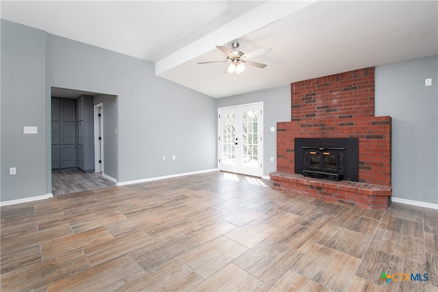 unfurnished living room featuring french doors, a wood stove, hardwood / wood-style floors, ceiling fan, and beam ceiling