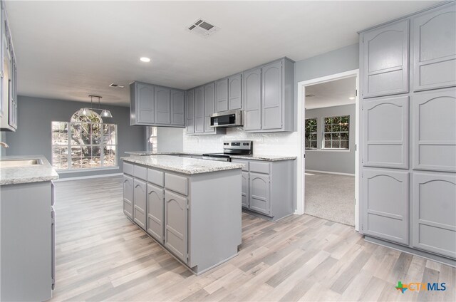 kitchen with a wealth of natural light, stainless steel appliances, gray cabinets, and light wood-type flooring