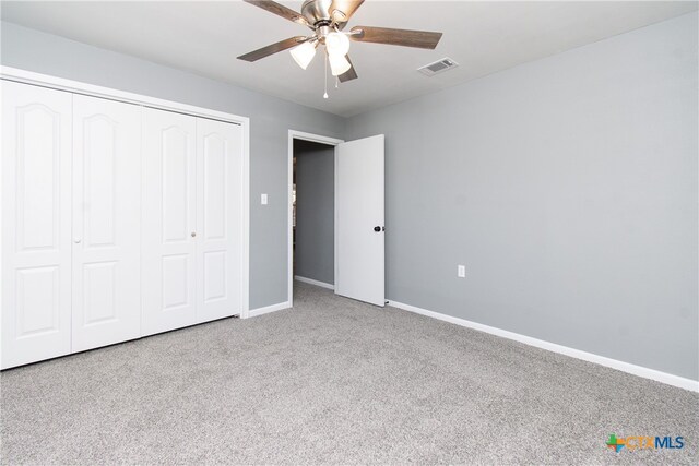 unfurnished bedroom with a closet, light colored carpet, and ceiling fan