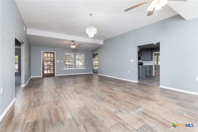 unfurnished living room with wood-type flooring and ceiling fan with notable chandelier