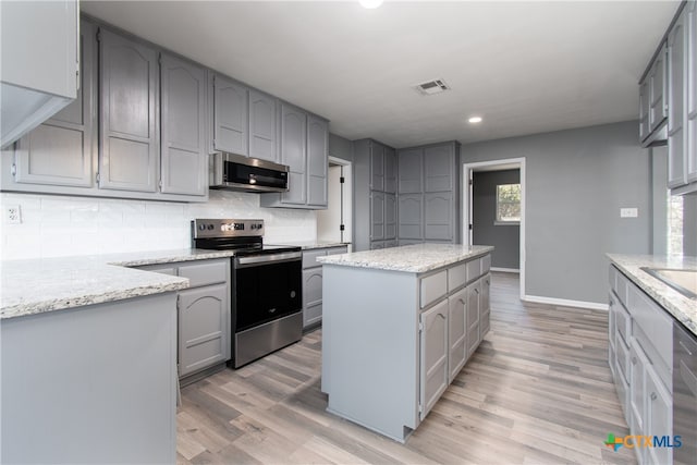 kitchen featuring gray cabinets, appliances with stainless steel finishes, light hardwood / wood-style floors, and a kitchen island