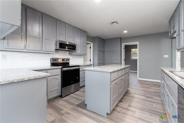 kitchen featuring gray cabinets, appliances with stainless steel finishes, light hardwood / wood-style floors, and a kitchen island