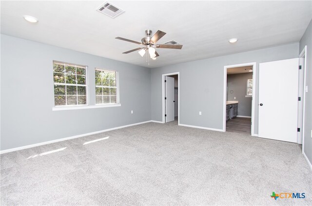 unfurnished bedroom with a walk in closet, ceiling fan, ensuite bath, and carpet floors