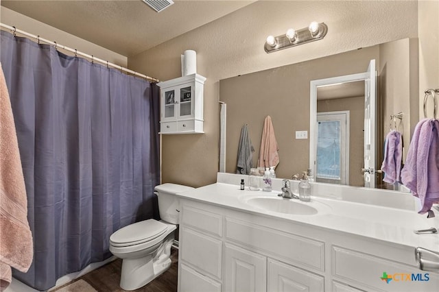 1205 Bowen Ave, Copperas Cove, TX 76522 - bathroom with toilet, vanity, wood finished floors, a textured ceiling, and a shower with curtain
