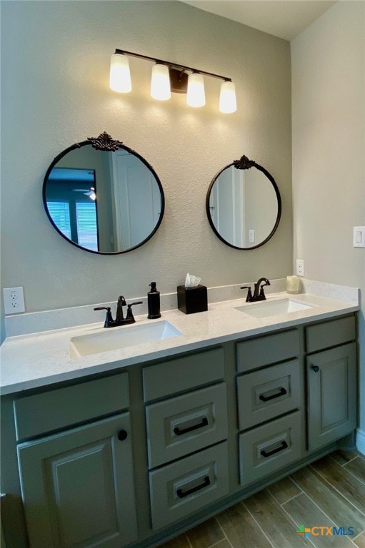 bathroom with double vanity, wood finish floors, and a sink