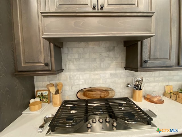 kitchen featuring stainless steel gas cooktop, decorative backsplash, and light countertops