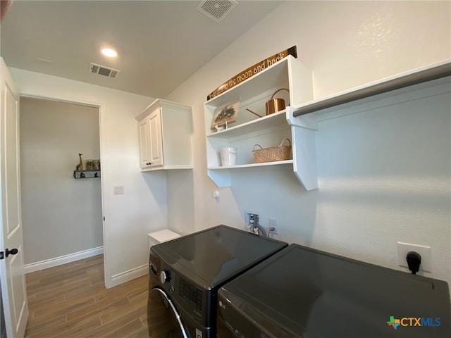 laundry room featuring visible vents, baseboards, washer and clothes dryer, wood finished floors, and cabinet space