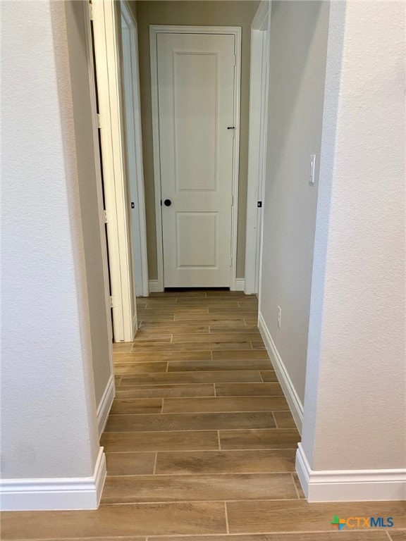 hall featuring baseboards and wood finish floors