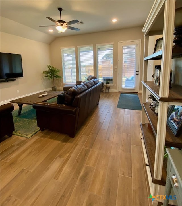 living room with a ceiling fan, lofted ceiling, light wood-style floors, and a wealth of natural light