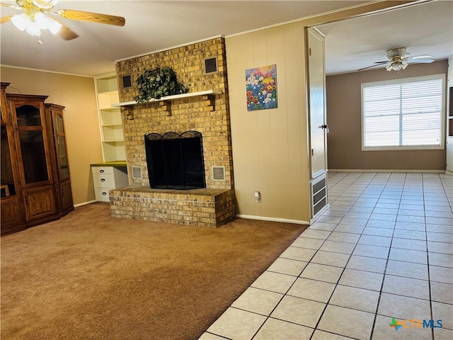 living room with built in shelves, ceiling fan, crown molding, carpet floors, and a fireplace