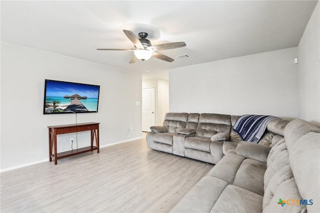 living area featuring light wood-type flooring, ceiling fan, visible vents, and baseboards