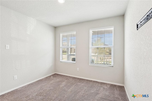 carpeted empty room featuring a textured ceiling, a textured wall, and baseboards